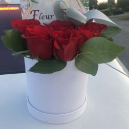 Red roses arranged in a white hat box with a ribbon