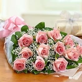Bouquet of pink roses wrapped in pastel paper with ribbon
