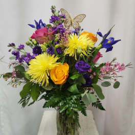 Mixed bouquet in a glass vase with yellow, purple, pink, and orange flowers