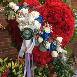 Large red floral standing spray with white and blue accents and a ribbon