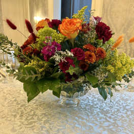 Mixed bouquet in a clear glass vase with orange and burgundy flowers
