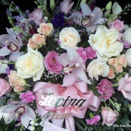 Pink and white floral spray with roses and orchids, accented by a pink ribbon