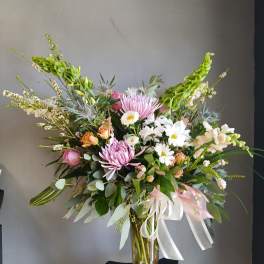 Mixed bouquet of pink and white flowers in a glass vase with ribbon
