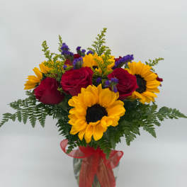 Bouquet of red roses and yellow sunflowers in a glass vase