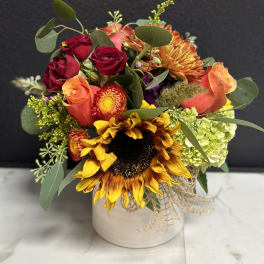 Mixed bouquet with sunflowers, roses, and hydrangea in a white vase
