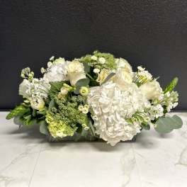 Low white floral arrangement in a rectangular glass vase