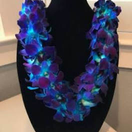 Purple orchid lei draped over a black bust display