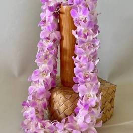 Purple orchid lei draped over a carved wooden vase