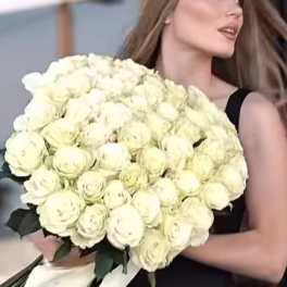 Woman holding a large bouquet of white roses with long ribbon tails