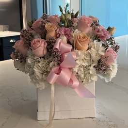Pink and peach roses with white hydrangeas in a white box, tied with a pink ribbon
