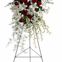 Standing floral spray of red roses and white lilies on an easel