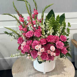 Large pink and white floral arrangement with roses and snapdragons in a white ceramic pot.