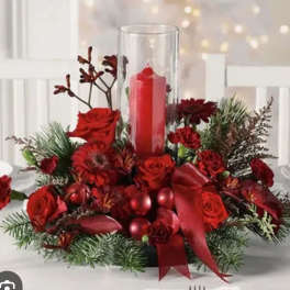 Red floral centerpiece with a tall glass candle holder and red candle