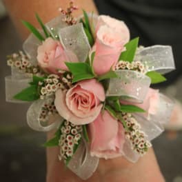 Pink rose corsage with silver ribbon and small white filler flowers