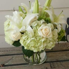 White lilies and roses arranged in a clear glass vase