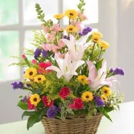 Mixed flower arrangement in a wicker basket with lilies and daisies