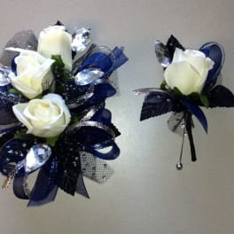 White rose corsage and boutonniere with navy ribbon and silver accents