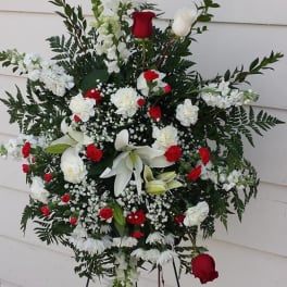 Standing funeral spray with red and white flowers on a black easel