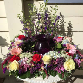 Large mixed flower arrangement with a dark purple vase