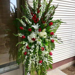 Standing floral spray with red roses and white lilies on a metal easel