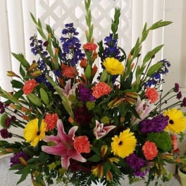 Large mixed flower arrangement in a white pedestal vase