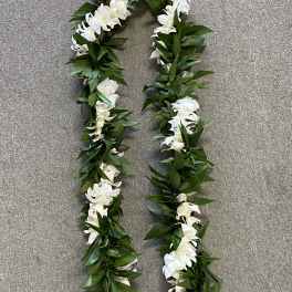 White flower lei with green leaves on a gray surface