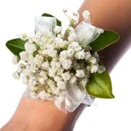 White floral wrist corsage with ribbon and green leaves
