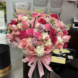 Pink and white rose arrangement in a black hatbox with a pink ribbon