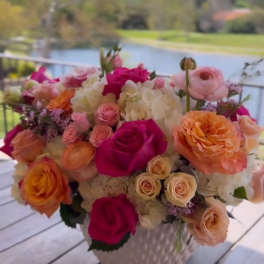 Mixed bouquet of pink, peach, and white roses in a white vase