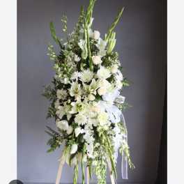 Tall white floral standing spray on an easel with ribbon