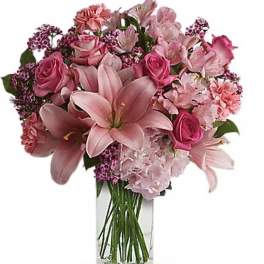 Pink lilies and roses arranged in a clear glass vase