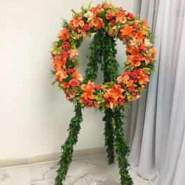Large floral wreath on a stand with orange and pink blooms