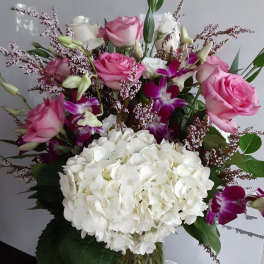 Bouquet of pink roses, white hydrangea, and purple orchids in a vase