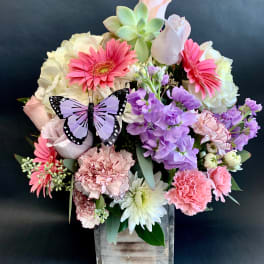 Mixed pink and purple bouquet in a wooden box with a butterfly decoration