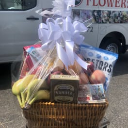 Gift basket with fruit, cookies, tea, and a white ribbon bow