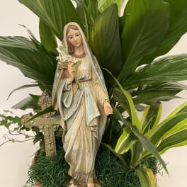 Potted religious statue surrounded by broad green foliage