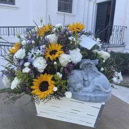 White and yellow floral arrangement in a wooden box with a stone angel figure