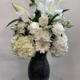White floral arrangement in a black vase with a decorative butterfly
