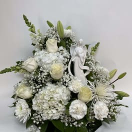 White floral arrangement with roses, lilies, and an angel figurine