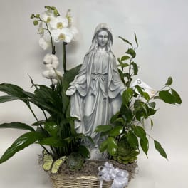 White orchids and greenery arranged around a statue in a basket.
