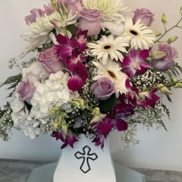 Lavender roses and white daisies in a white vase with a cross emblem
