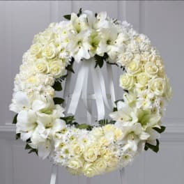White floral wreath with roses and lilies on a stand