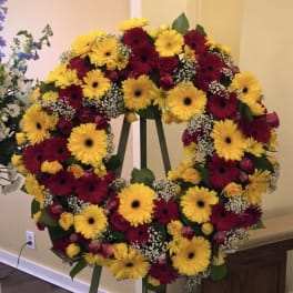 Large floral wreath on an easel with yellow and burgundy blooms