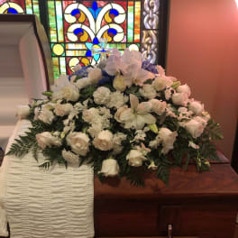 White floral casket spray with a cross in a church setting