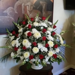 Large standing arrangement of red roses and white chrysanthemums in a white urn