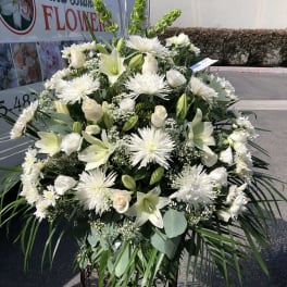 Large white funeral spray with lilies, roses, and spider mums