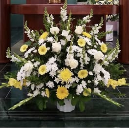 Large white and yellow floral arrangement in a white container