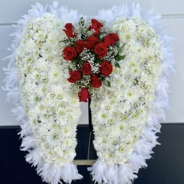 Heart-shaped white floral wreath with red roses on a stand