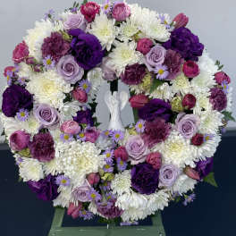 Heart-shaped floral wreath with purple, pink, and white blooms on an easel