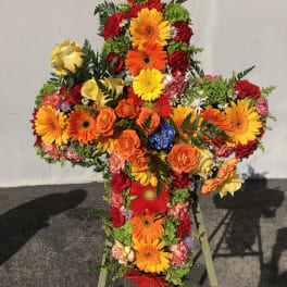 Cross-shaped floral spray with bright mixed blooms on a stand